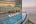 a pool with chairs on the edge of a building