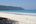 a beach with trees and blue water