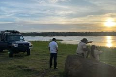a group of people standing on a rock by a lake