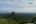 a view of a forest and mountains from a cliff