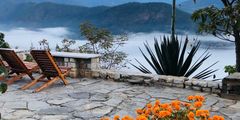 chairs on a patio overlooking mountains and clouds