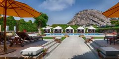 a pool with white tents and a large rock in the background