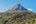 a mountain with trees and blue sky