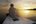 a man sitting on a dock looking at the sunset