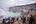 a group of people standing on a rocky hill looking at a crater
