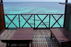 a deck with chairs and a railing overlooking the ocean