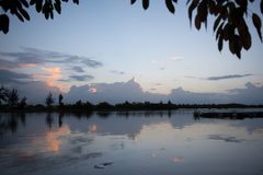 a body of water with trees and clouds in the sky