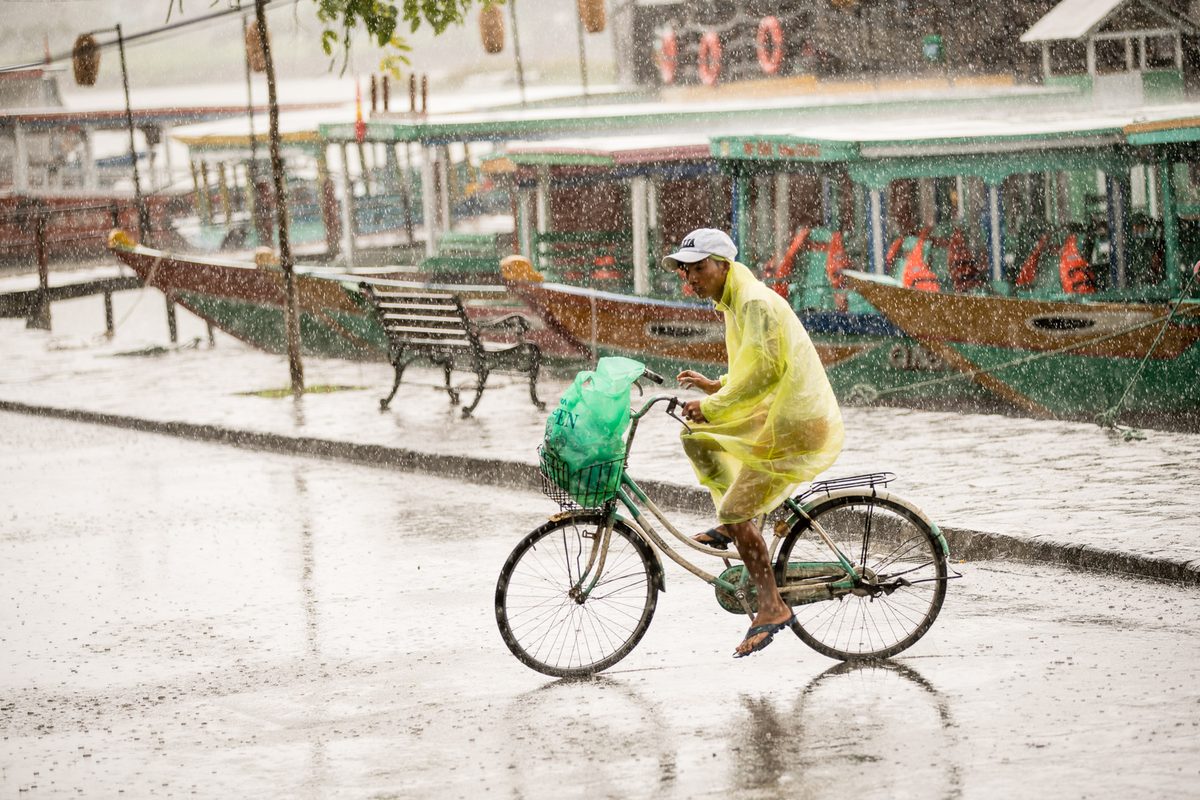 People riding bicycles whilst holding umbrellas