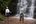 a man and woman standing in front of a waterfall