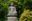 a statue of a person sitting on a pedestal surrounded by trees