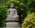 a statue of a person sitting on a pedestal surrounded by trees
