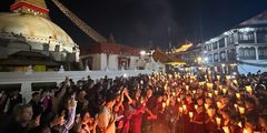 a group of people holding candles and standing in front of a building