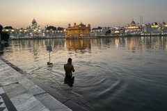 a man standing in water with a building in the background