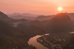 a river running through a valley with mountains and a city in the distance