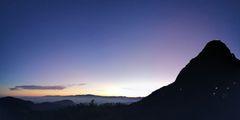 a silhouette of a mountain with a sunset in the background