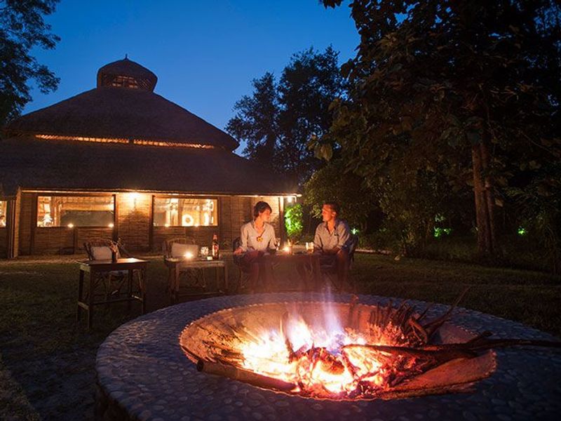 Couple sat at fire pit at night at Karnali Lodge