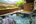 a hot tub with rocks and a railing