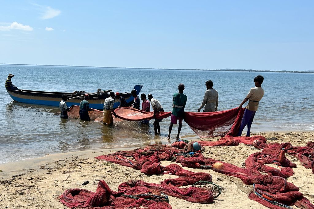 a group of people pulling up nets on a beach