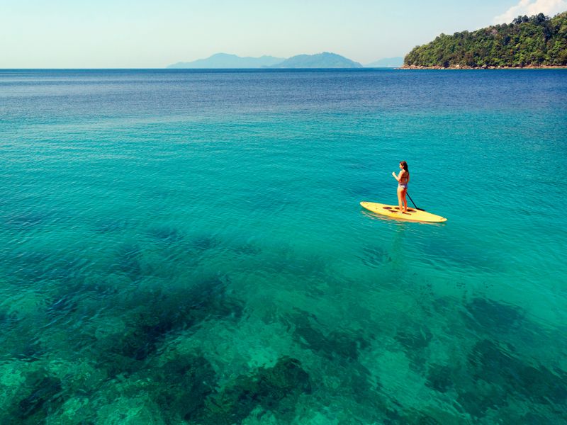 Woman paddle-boarding on a turquoise sea