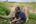 a man sitting next to an elephant