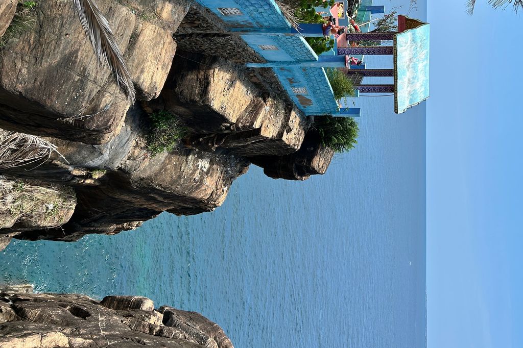 a blue building on a cliff overlooking the ocean