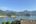 a house with a thatched roof surrounded by water and mountains