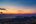 a cityscape with mountains and water in the background