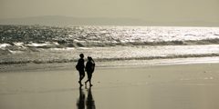a couple of people walking on a beach