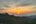 a sunset over a green hill