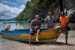 a group of men sitting on a boat on a beach