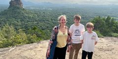 a woman and two boys posing for a picture on a rock
