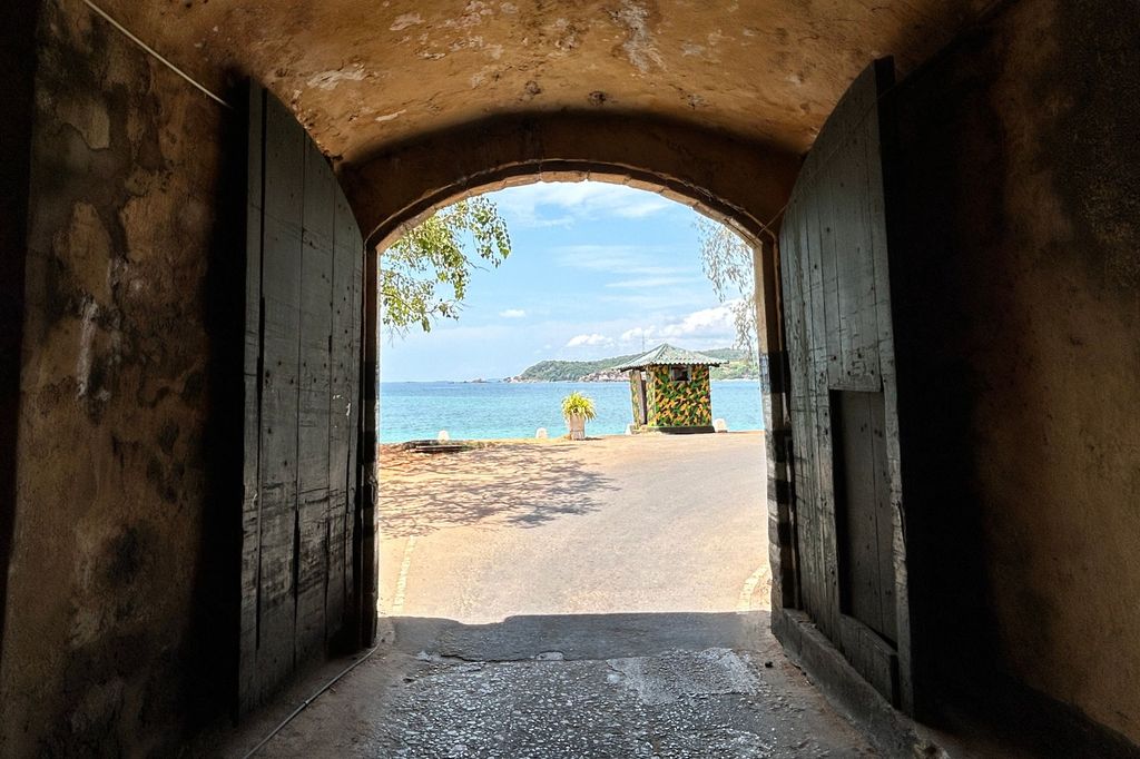 a tunnel with open doors and a beach and water in the background