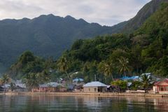 a body of water with houses and mountains in the background