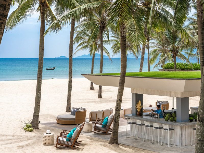 Beach bar with palm trees at Four Seasons Nam Hai Hoi An